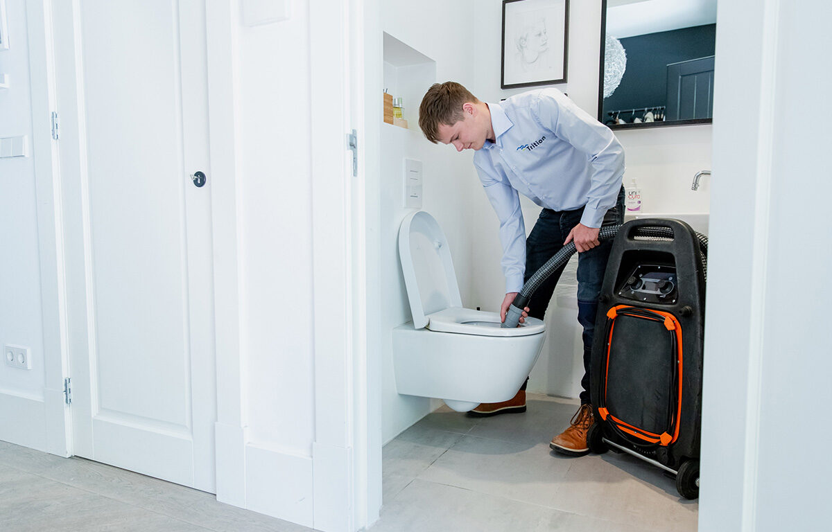 Medewerker voert lekdetectie uit in toilet met speciale apparatuur